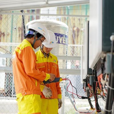 Electricistas con casco trabajando en un cuadro eléctrico